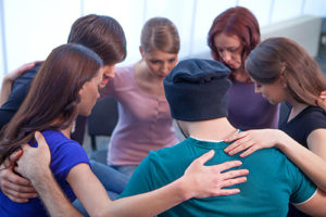 Group of people sitting in a circle. Hugging each other at stimulant detox center