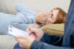 woman on couch with hands over mouth in Depression treatment program