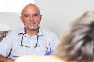 older adult man smiles and looks ahead while talking to a person about alzheimer's and dementia treatment