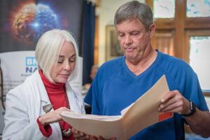 a medical professional shows a patient their chart and explains how neurodegenerative diseases treatment can help them