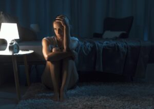 person sitting on floor in the dark struggling with opioid detox symptoms