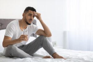 person in bed with headache struggling with alcohol detox symptoms