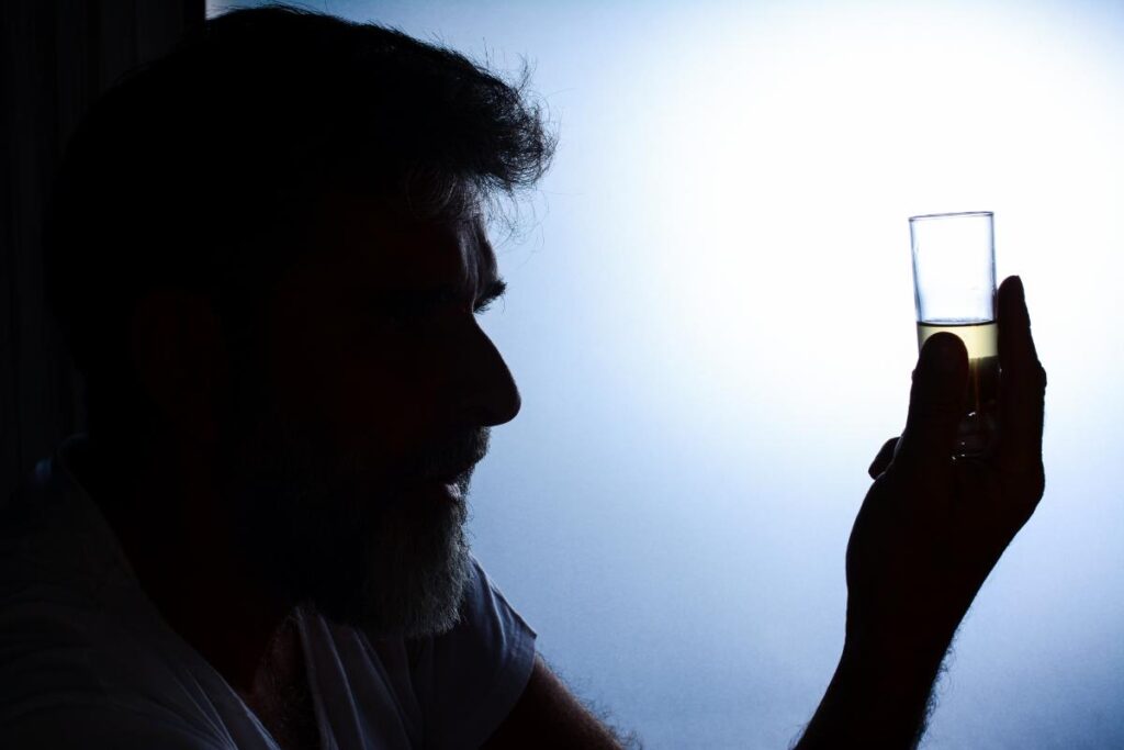 silhouette of person holding shot of tequila wondering how to resist alcohol cravings