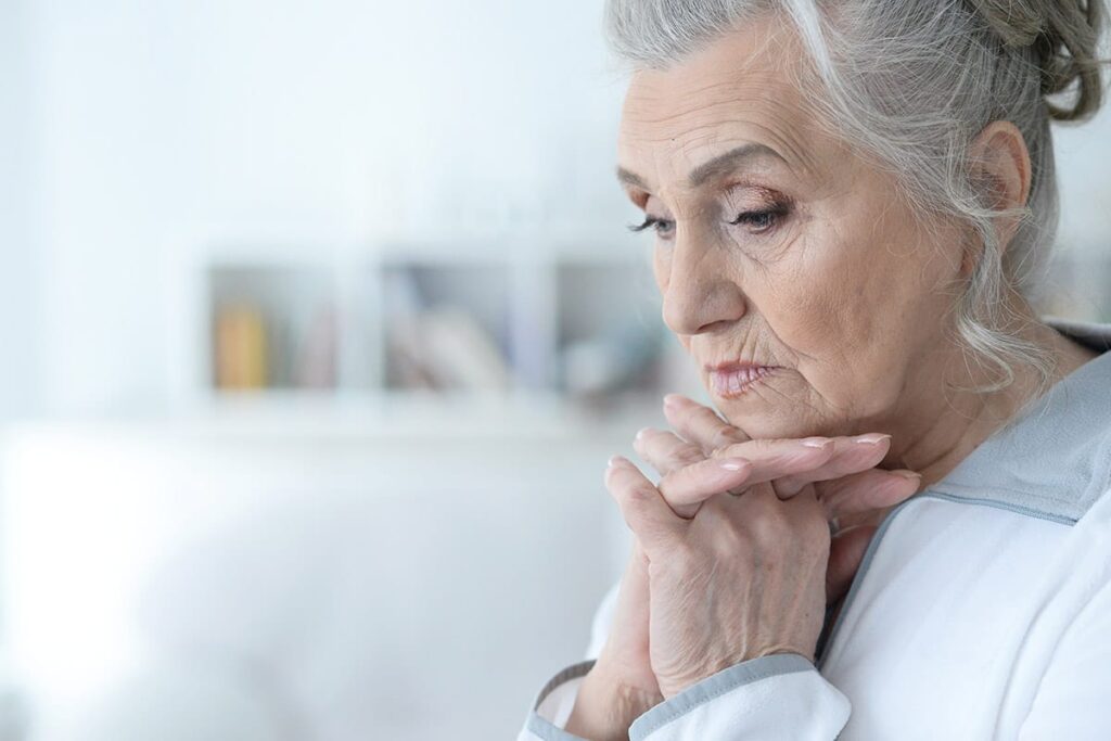 older woman with hands folded wondering about signs of early onset alzheimers