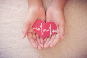 person holding heart decorated with ekg line tracings to illustrate healthy benefits of andrew huberman supplements