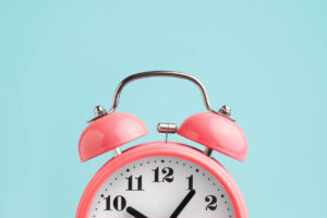 red old fashioned alarm clock on blue background to illustrate the best time to take NAD